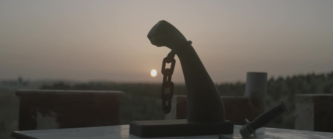 A man walks away from a sculpture of a chained fist