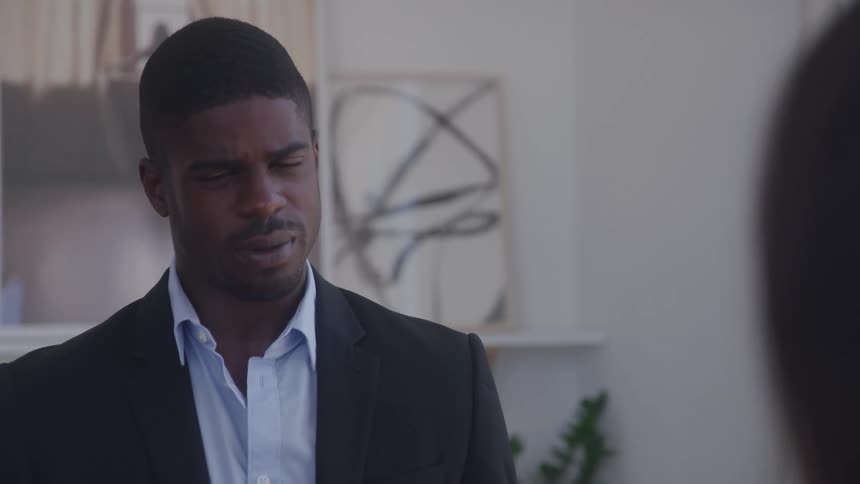 A man in a suit is talking to a woman in an office setting