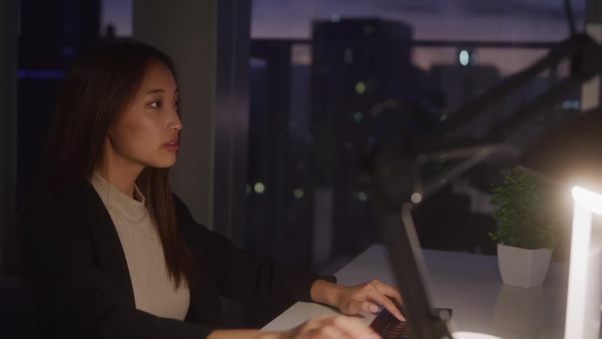 Woman in her home office typing on a keyboard placed on a desk