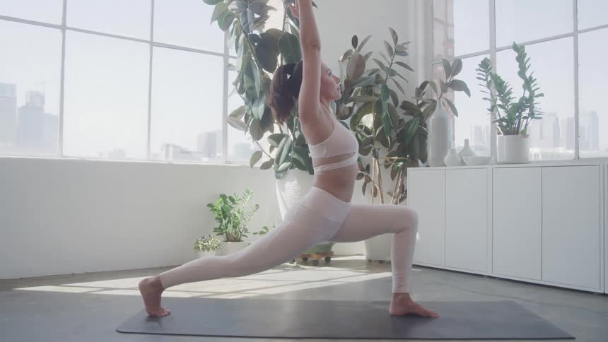 The woman is doing yoga and stretching her legs and arms