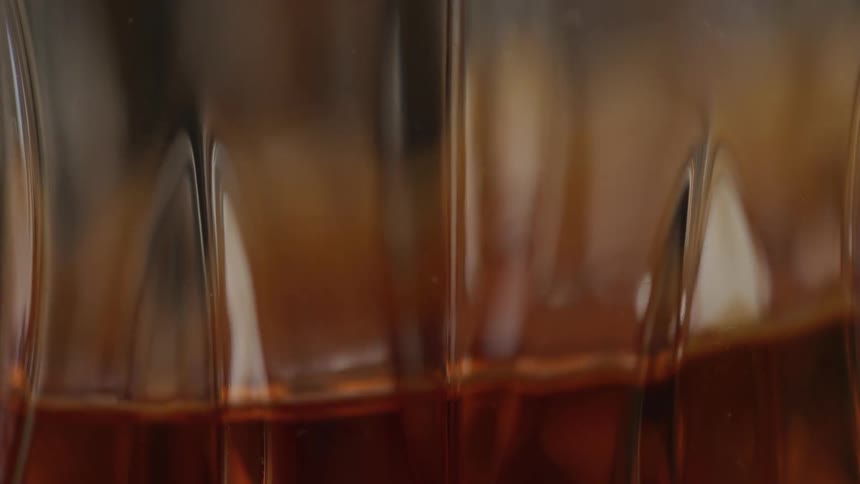 Extreme closeup of dark liquid swirls in clear glass