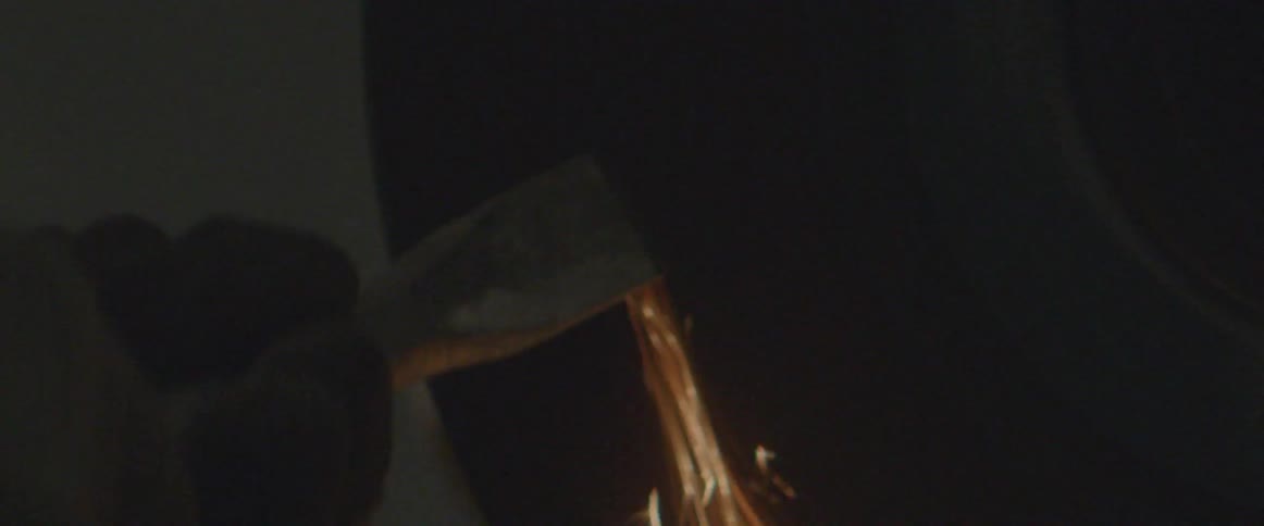 A man grinds a metal chisel on a grinding wheel