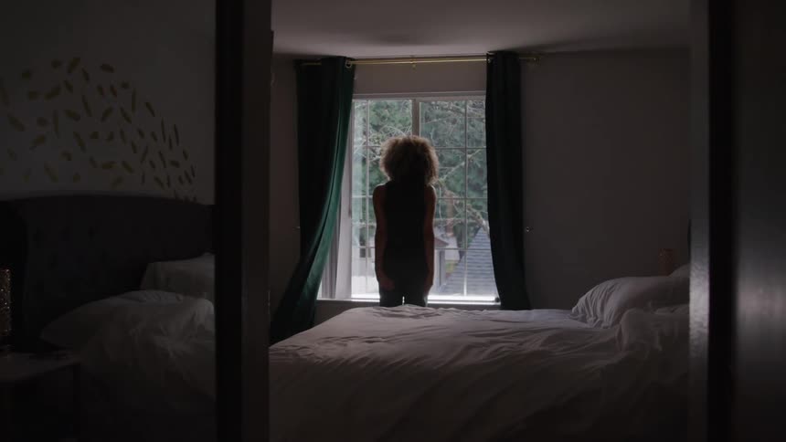 View of a mirror in a room and a woman opening the curtain