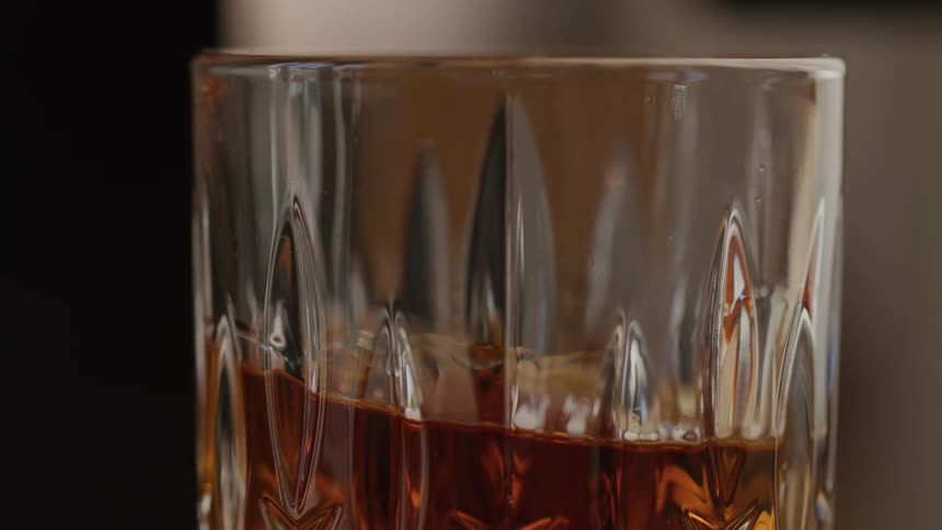 A hand places an amberdrink down