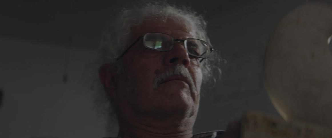A man in glasses works on a sculpture