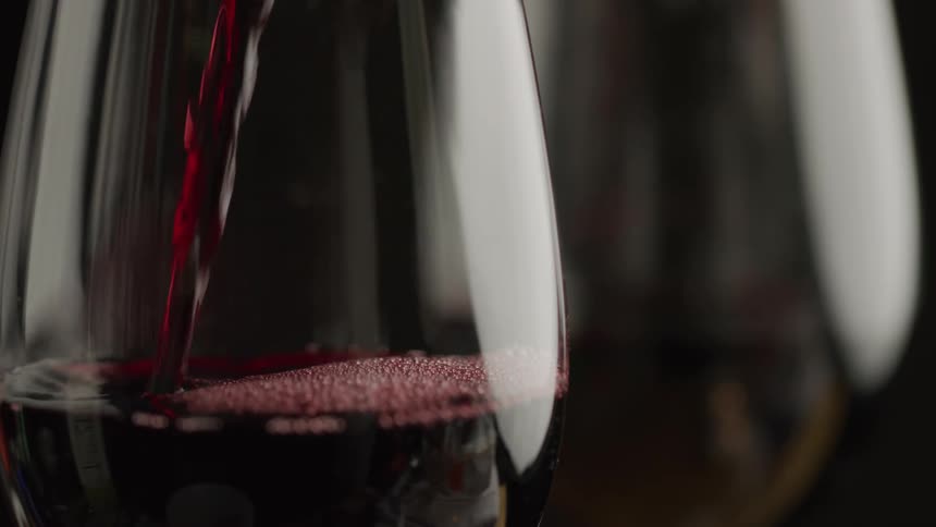 Red wine is being poured into the glass