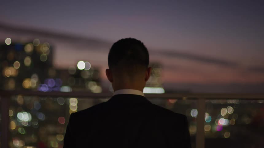 A man is looking out over the city from the balcony