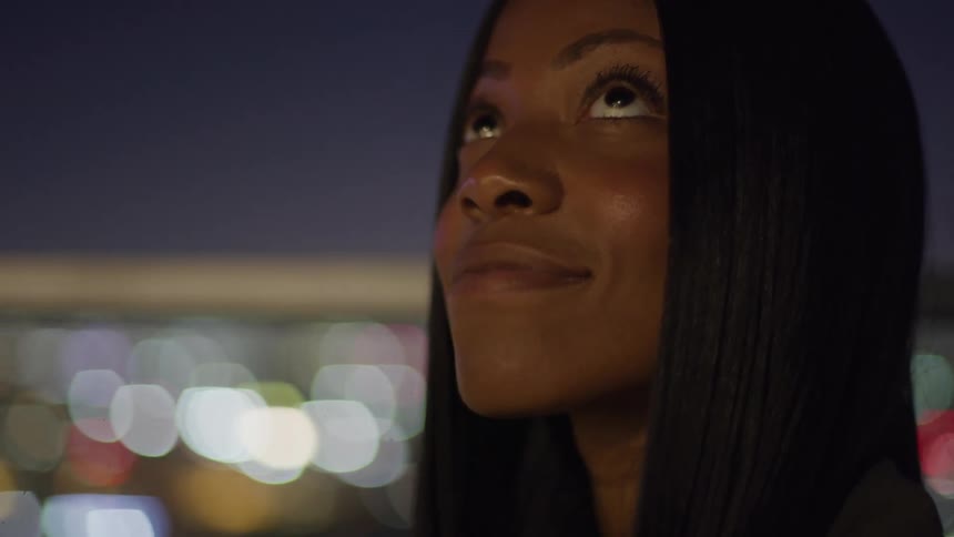 Woman smiling while looking up at the night sky