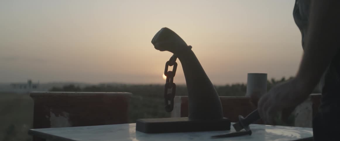 A person works on a sculpture of an arm