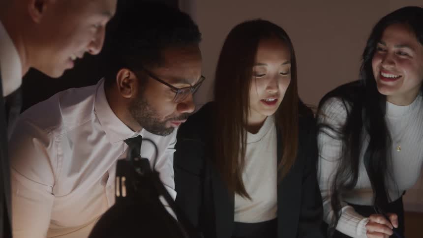 A group of office employees crowd together and brainstorm ideas