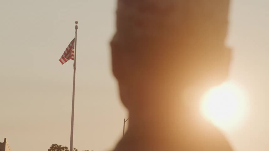 Military man in cap observing the united states flag