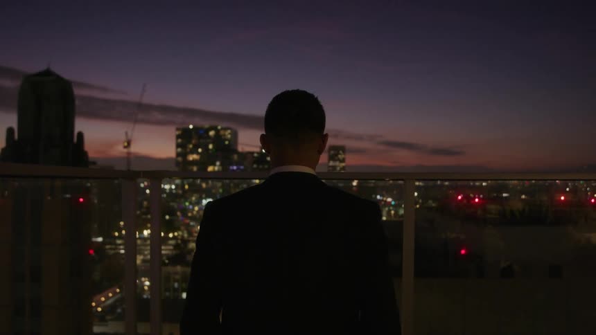 A man is standing on the balcony at sunset