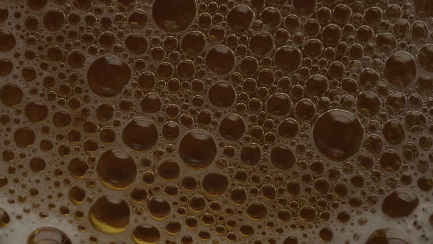 A dense cluster of goldenbrown bubbles forms a frothy surface