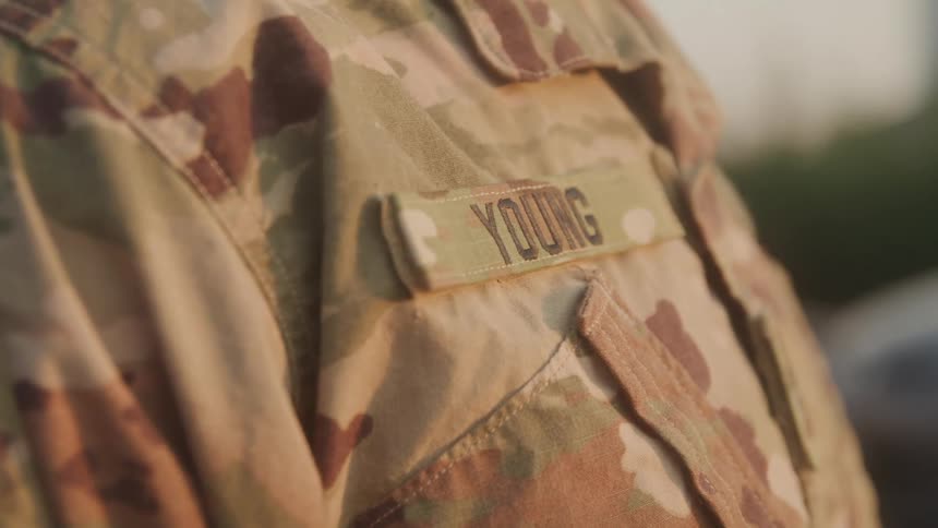 A camouflage military uniform displays the name tag young on the chest
