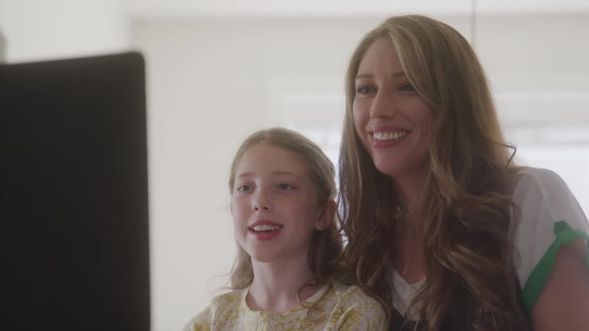 Mother and daughter waving goodbye in front of a laptop
