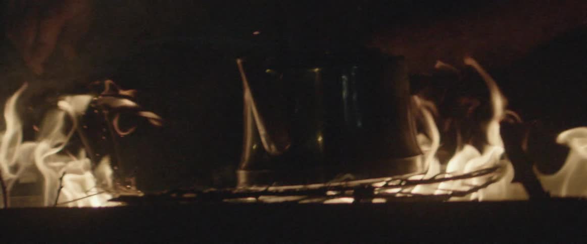The fire blazes around the pot on a campfire