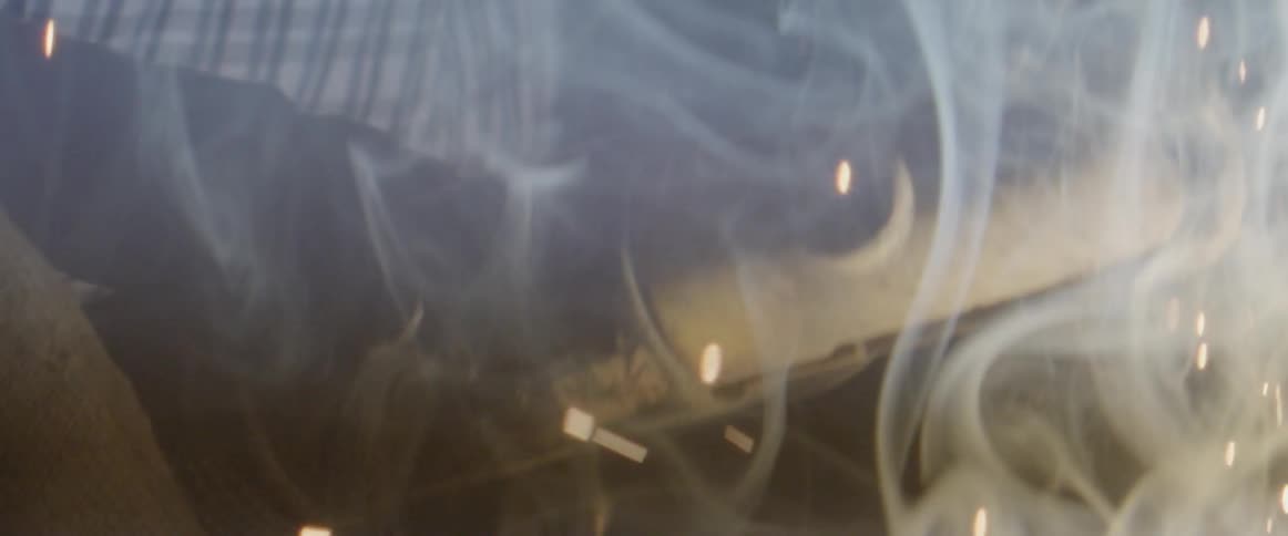 Sparks and smoke lift into the air as a man welds