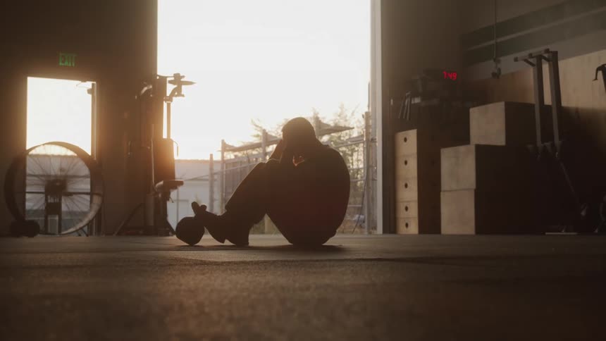A military man performs situps in a gym at sunset