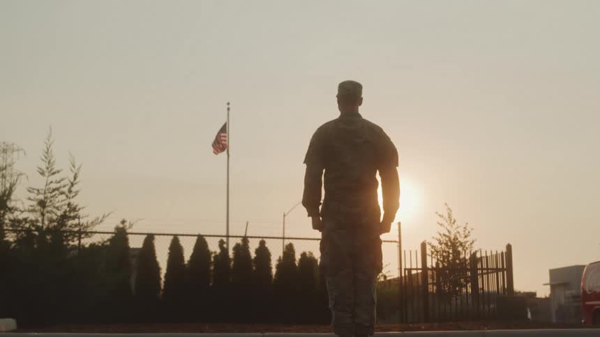 American soldier standing at attention in front of the flag