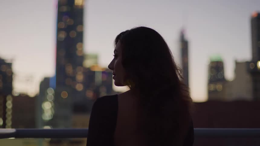 A woman on the balcony looks out over the city