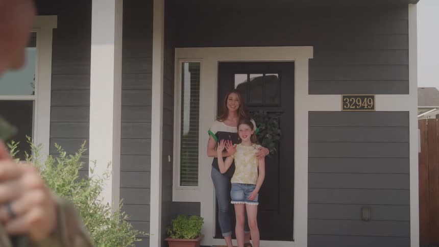 Man in military gear waving goodbye to his wife and daughter as he leaves for deployment