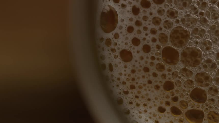 Highly detailed closeup shot of bubbles forming the head of a frothy beer