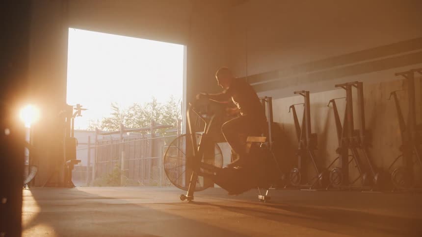 The man is pedaling on the exercise bike fast