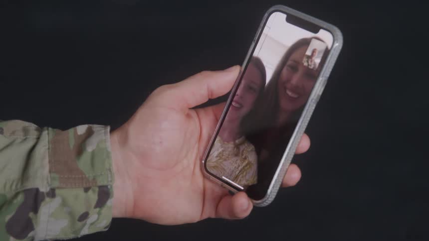 Close up of a military man waving at his family over a video call on a phone