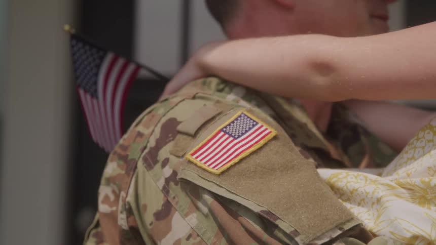 Smiling soldier holds a child in his arms with american flags in the background