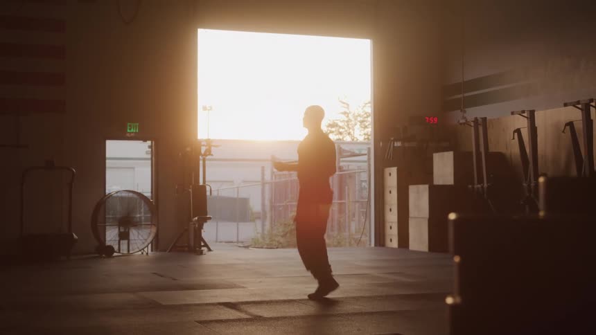 Silhouette of a man jumping rope in a gym