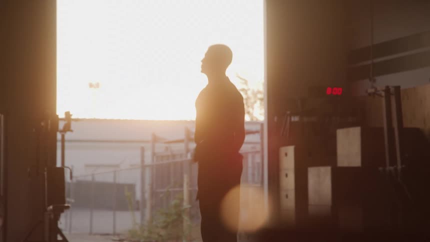 Man jumps rope at the entrance of a warehouse lit by sunset light