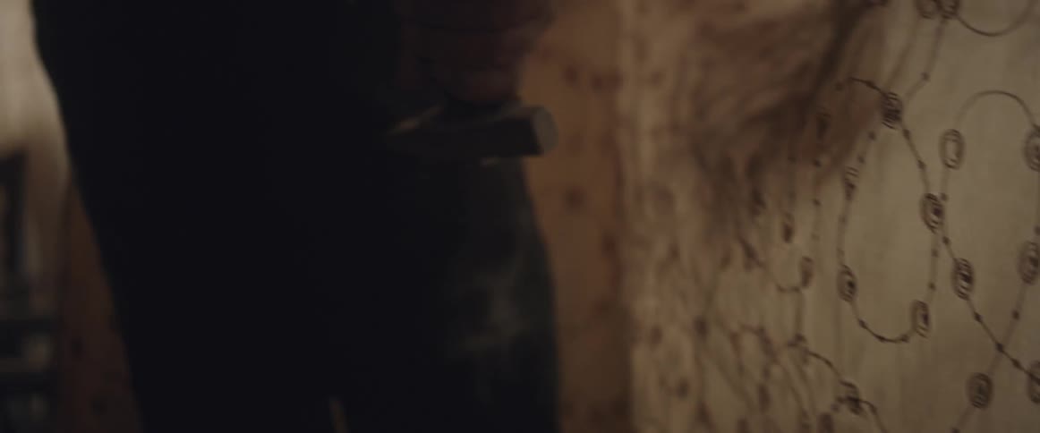 A person carrying a rock hammer walks toward the window
