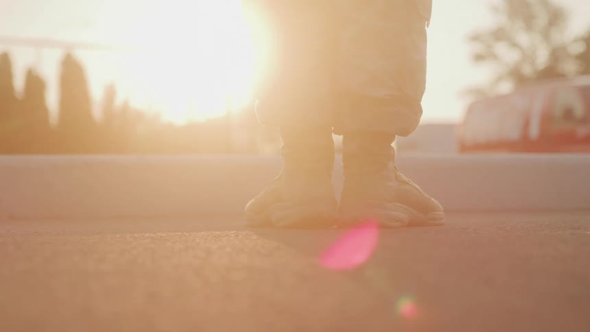 Close up of a dressed military personnels legs as they bring their feet together while standing outdoors at sunset
