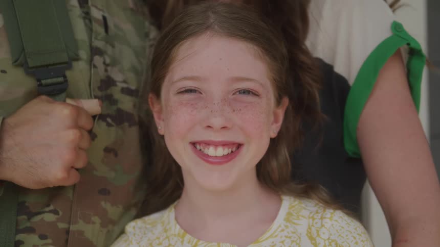 A girl is smiling while standing with two people