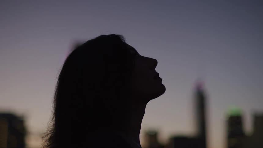 The woman looks up in the dark