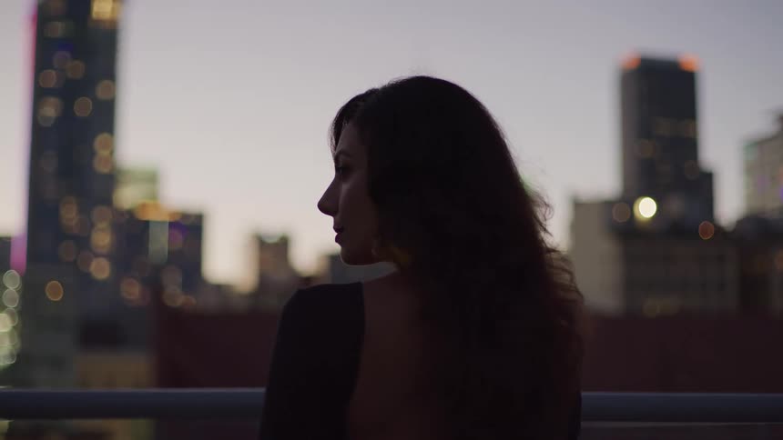 The woman watches the city as the sun sets