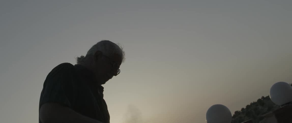 A man uses a tool to grind a rock while dust flies through the air