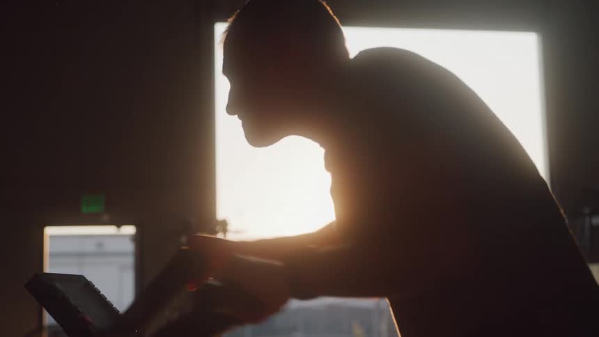 Man doing cardio in a gym shed with sunset reflection