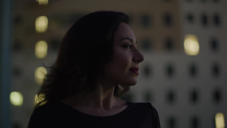 Woman with a happy expression in an outdoor setting with buildings in the background