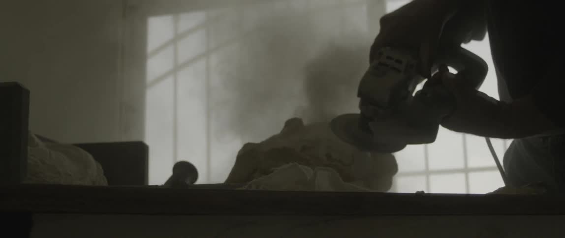A sander is carving stone in a dark room