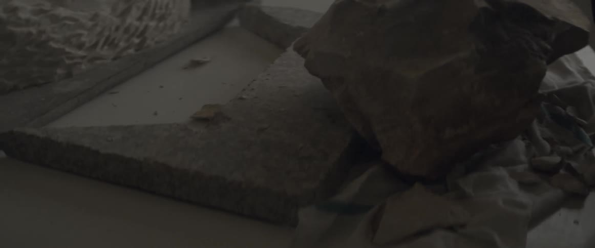 Stone chips fall to the table as a sculptor works