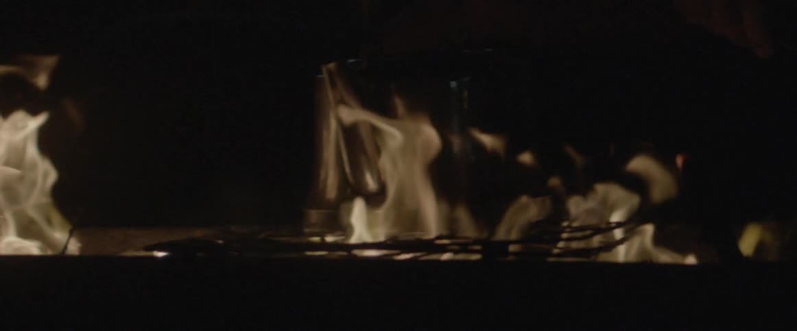 A pot sits on a fire cooking at night