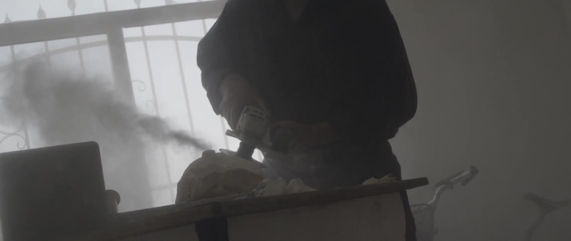A man uses a power tool to grind a rock