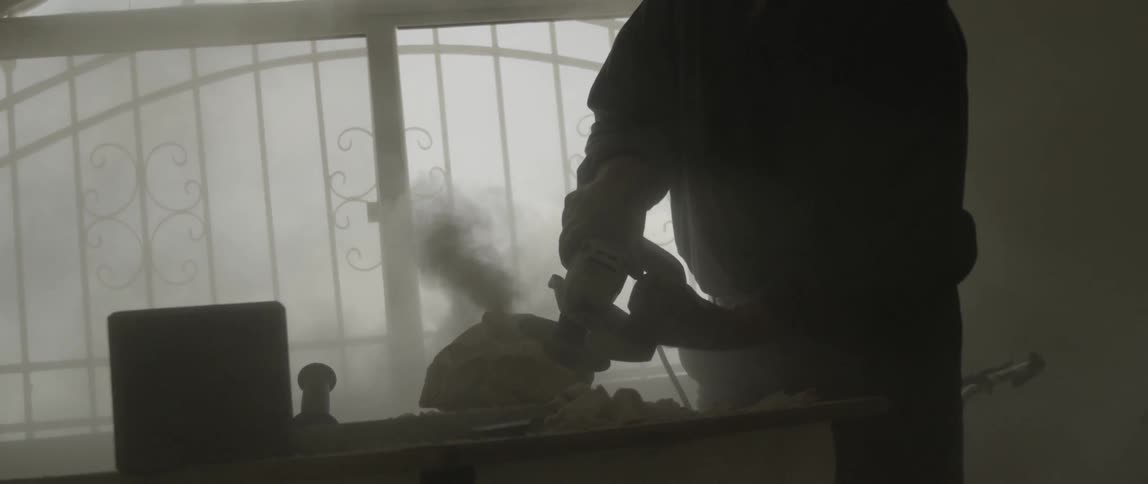 A man works with a grinder on a sculpture