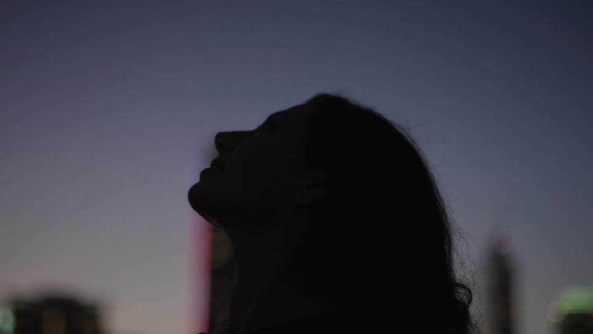 Silhouette of a woman outdoors with buildings in the background