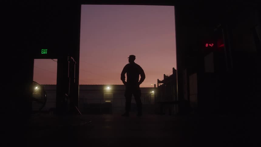 Silhouette of a man with his hand on his waist in a shed