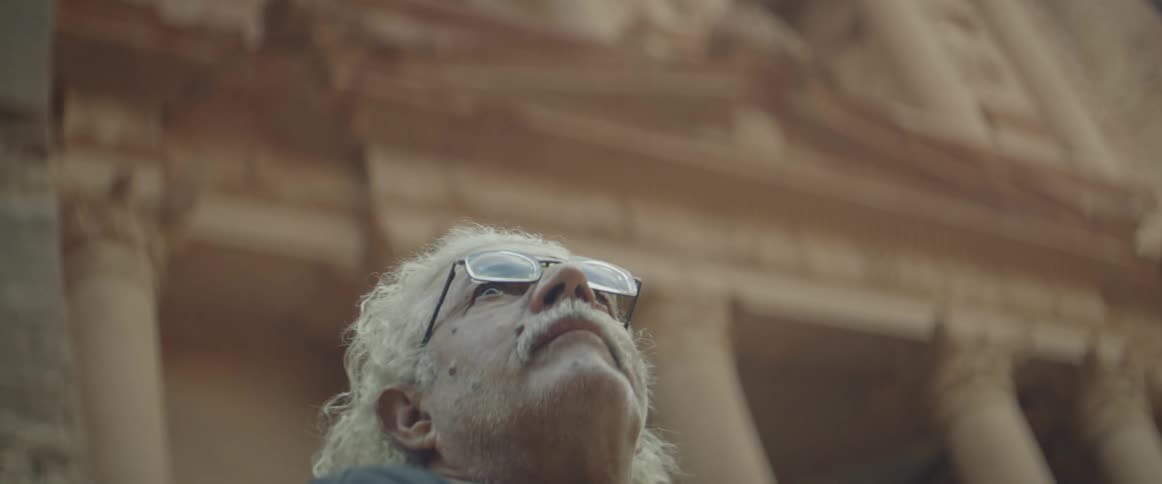 A man looks up at ancient ruins