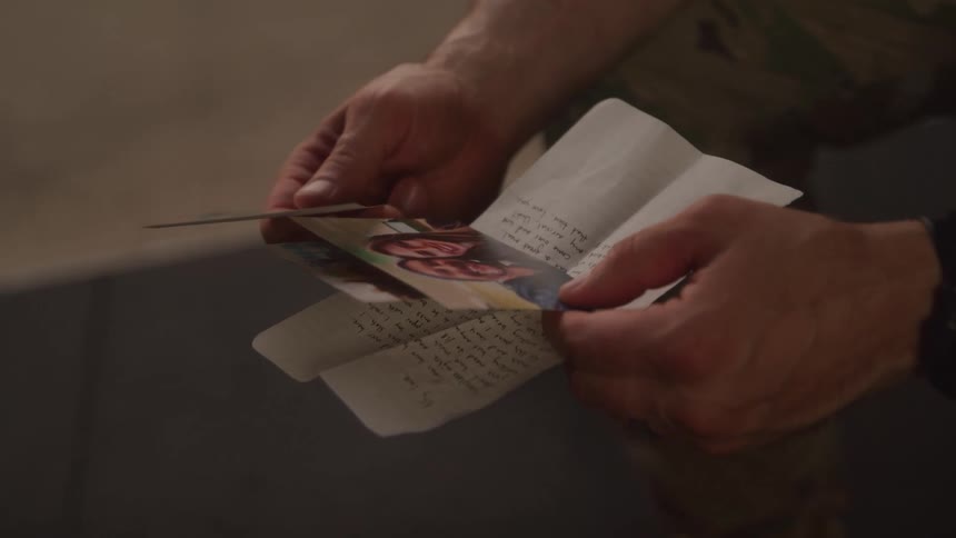 A soldier is looking at a note and photos
