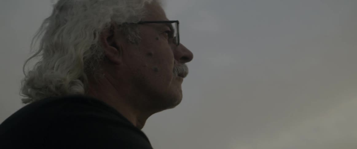 A man wearing glasses stands outside