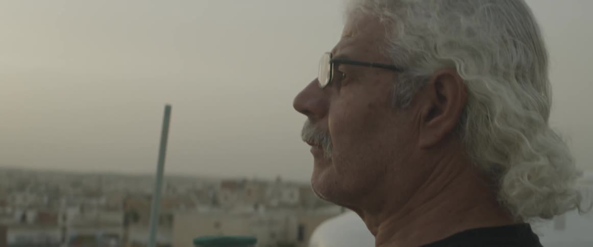 A man looks out over a city from a rooftop